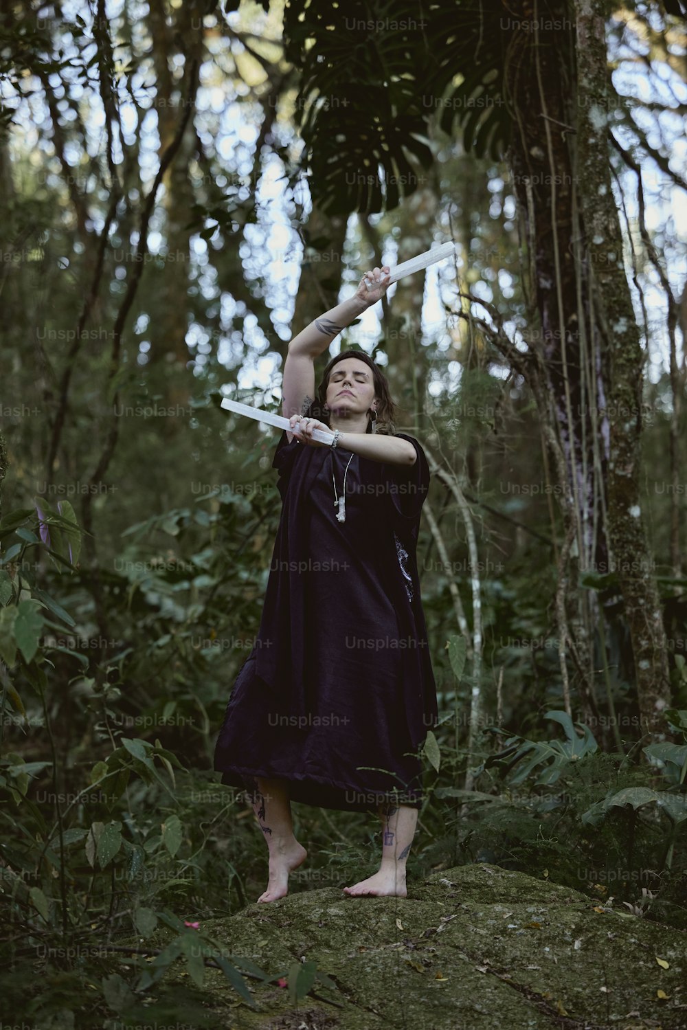 Una donna in un vestito viola che tiene una spada in una foresta