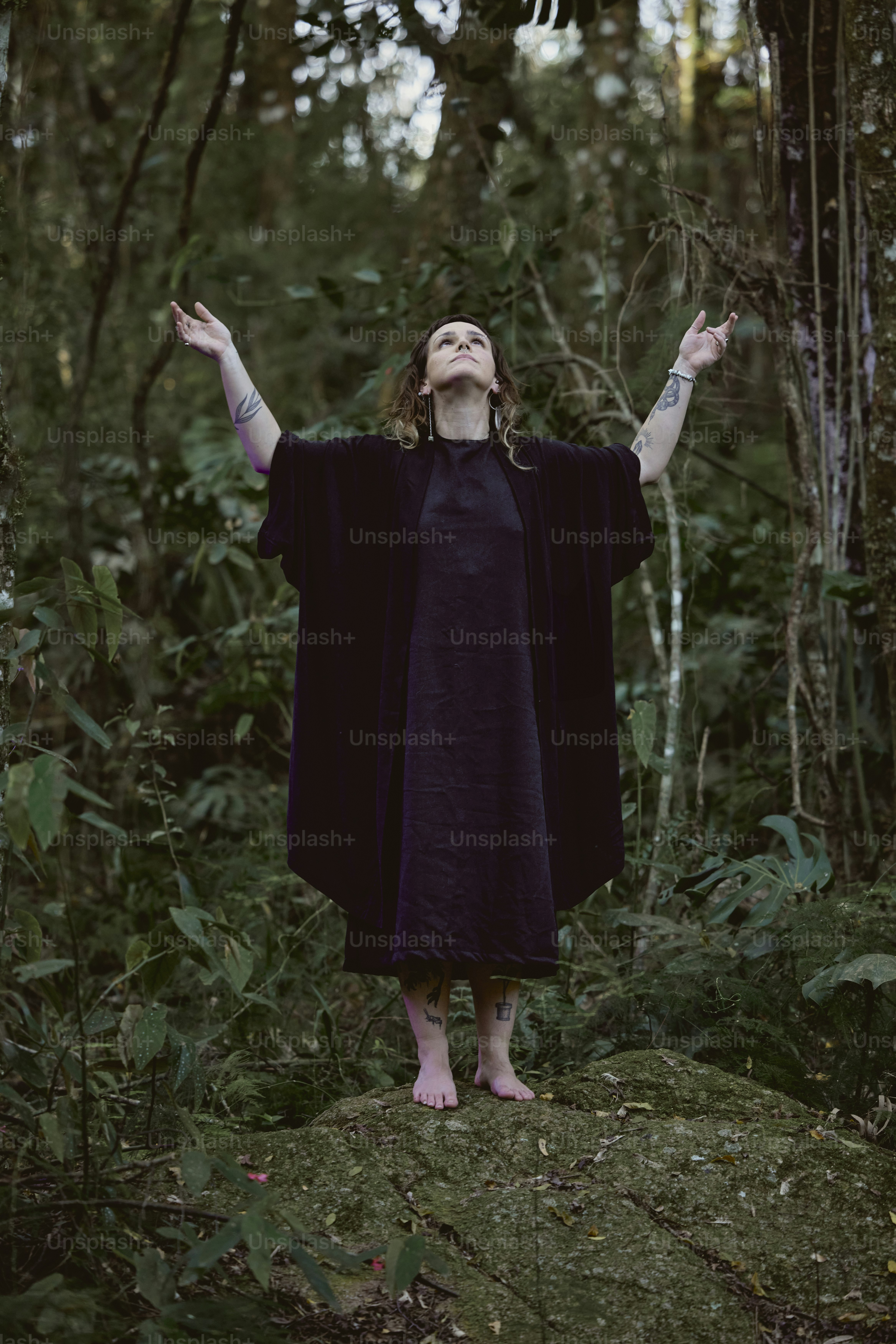 eine frau in einem lila kleid, die im wald steht