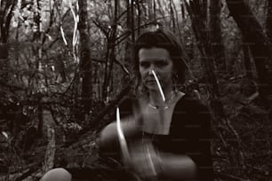 a woman sitting on the ground in the woods