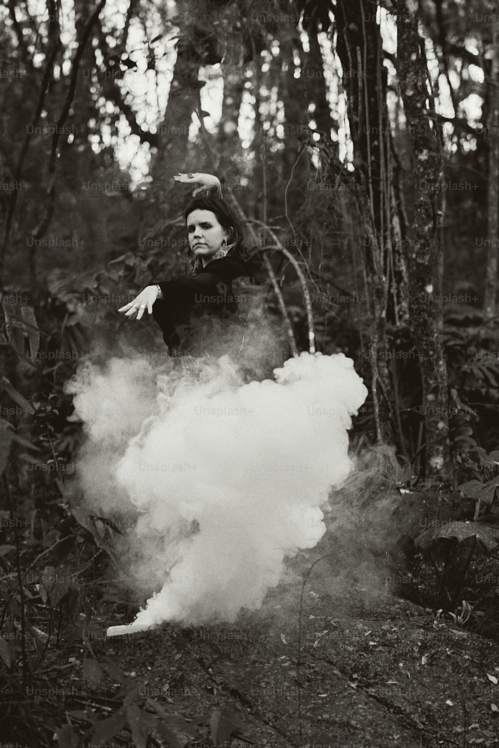 a woman standing in a forest with smoke coming out of her face