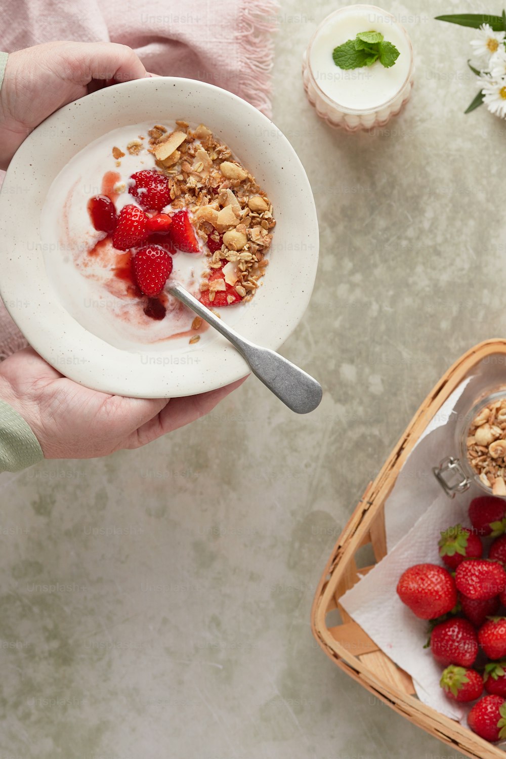 a person holding a bowl of granola and strawberries