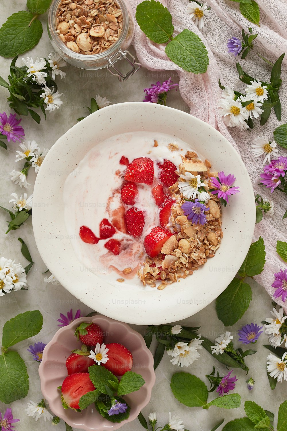 a bowl of yogurt, granola, and strawberries on a table