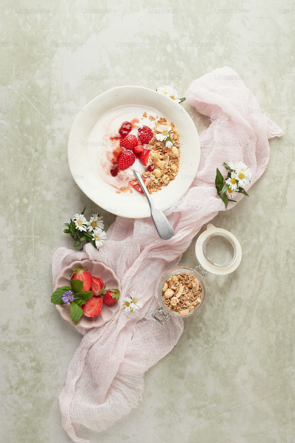 a bowl of granola with strawberries and a bowl of yogurt