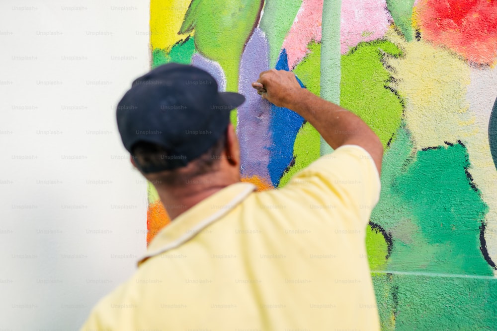 a man is painting a wall with colorful paint