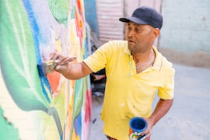 a man in a yellow shirt is painting a wall