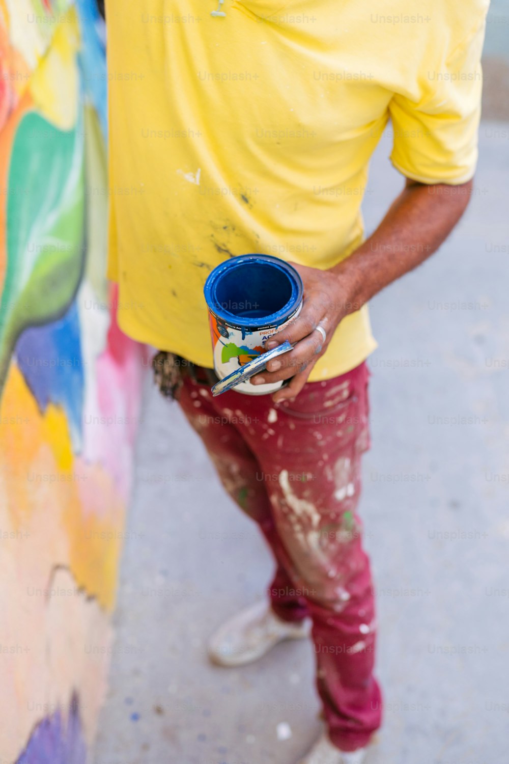 Un uomo con una camicia gialla tiene in mano un barattolo di vernice