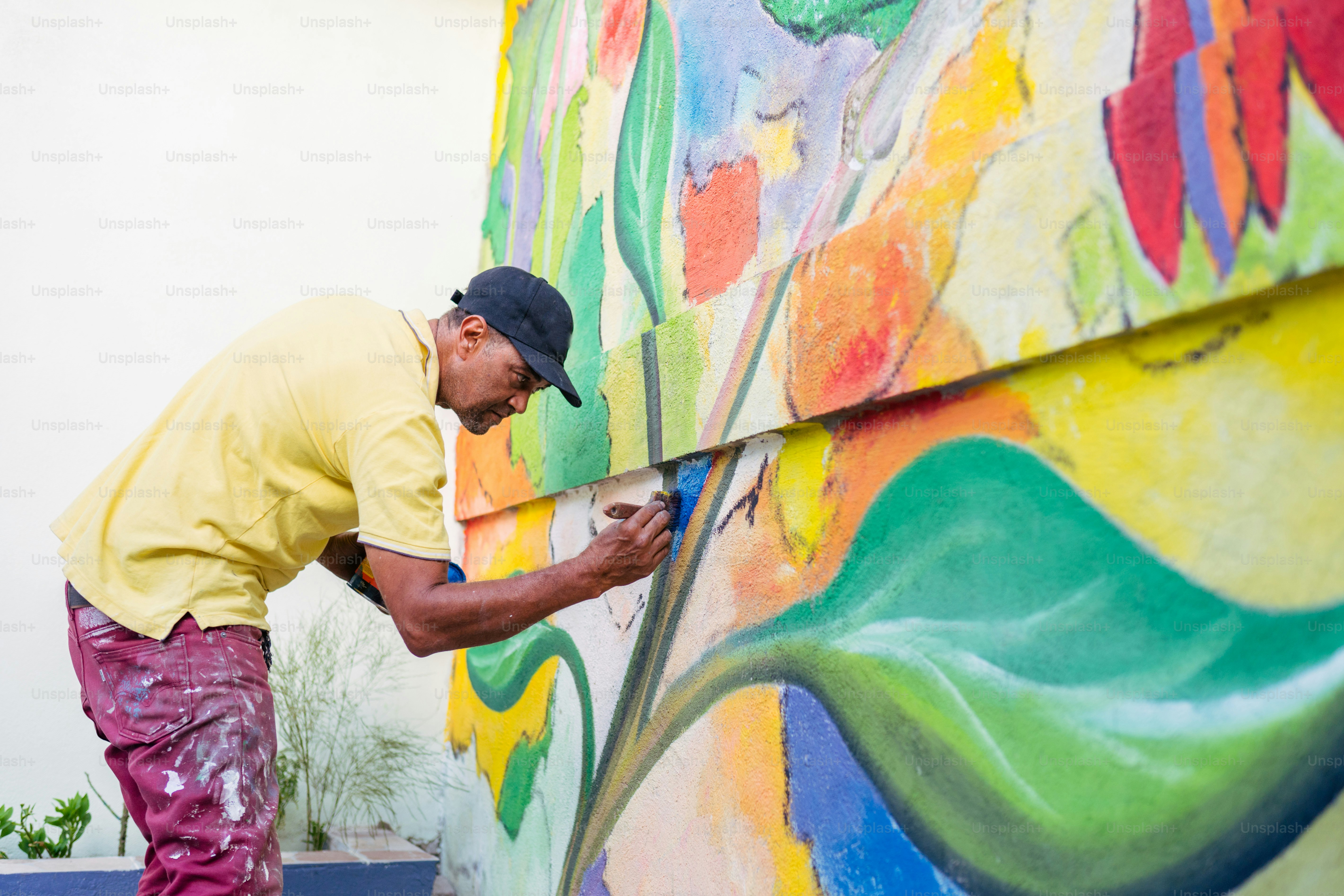 A man painting a wall with colorful paint photo – Painting Image on ...