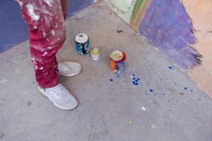 a person standing next to two cans of paint