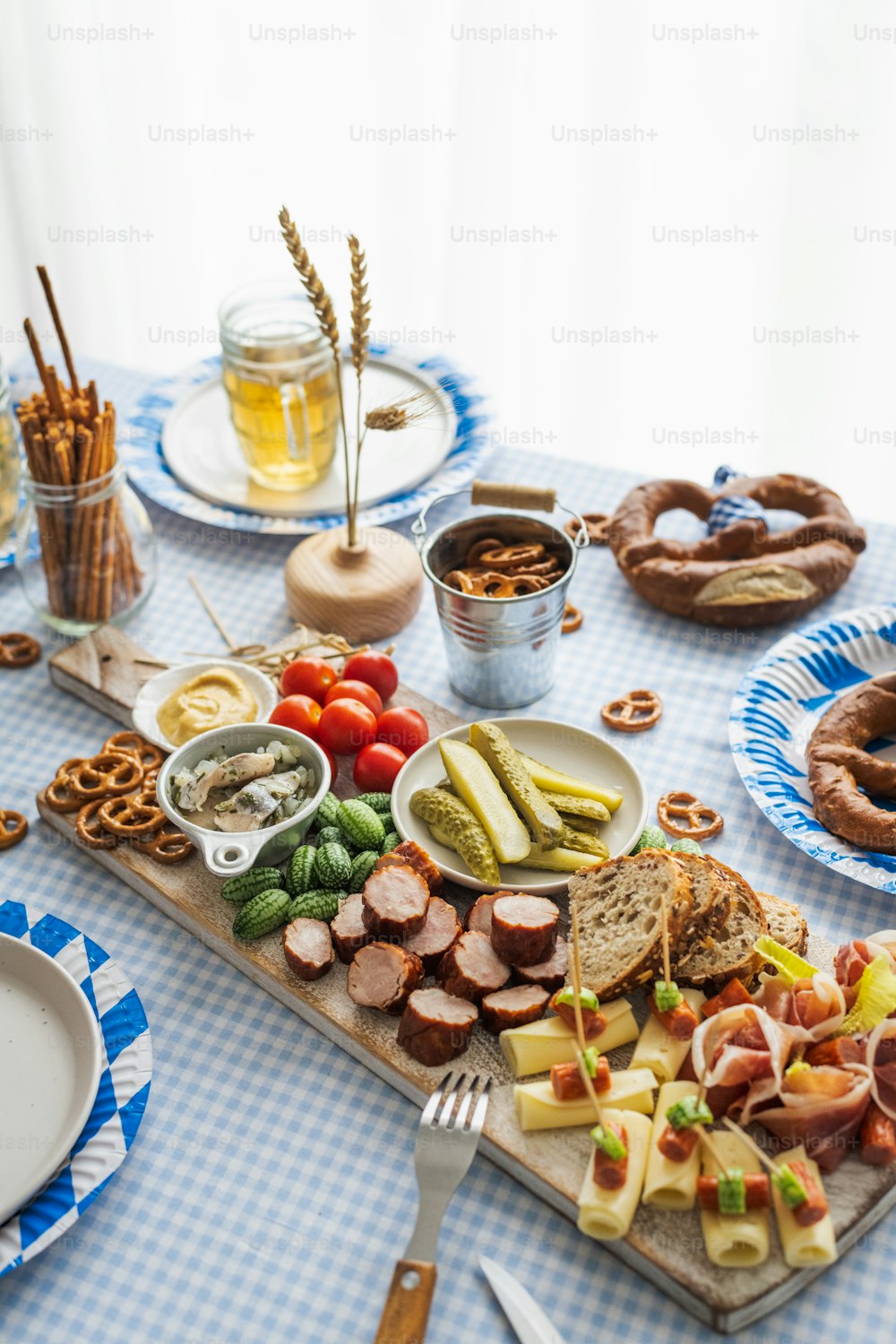 a table topped with plates of food and a tray of pretzels