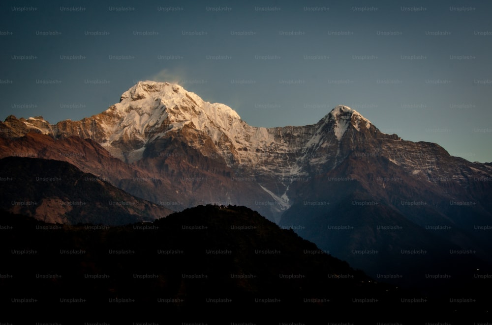 a view of a snow covered mountain from the top of a hill