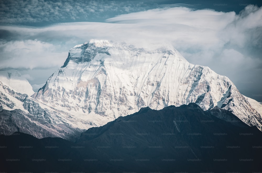 a large snow covered mountain in the middle of a cloudy sky