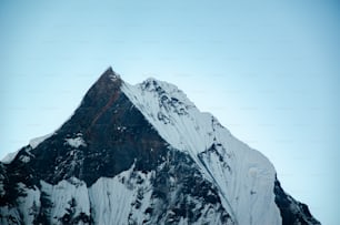 Una montagna innevata molto alta con uno sfondo del cielo