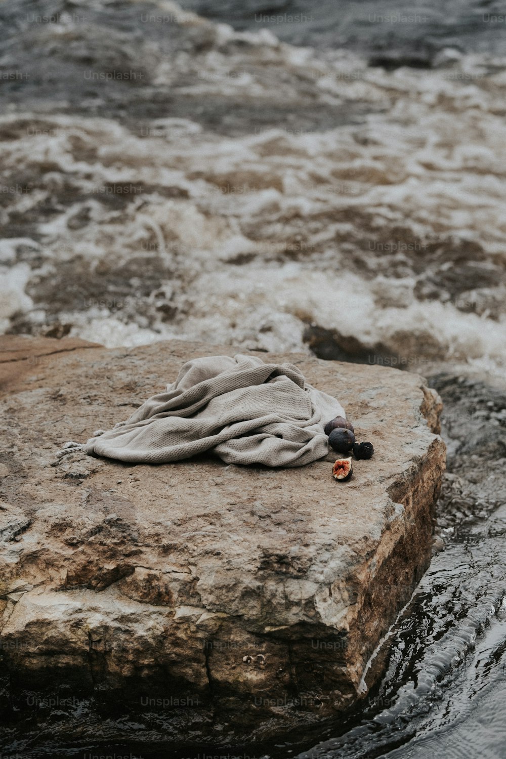 a blanket is laying on a rock in the water