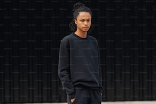 Un joven parado frente a una pared negra