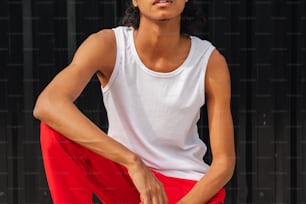 a woman in a white tank top and red pants
