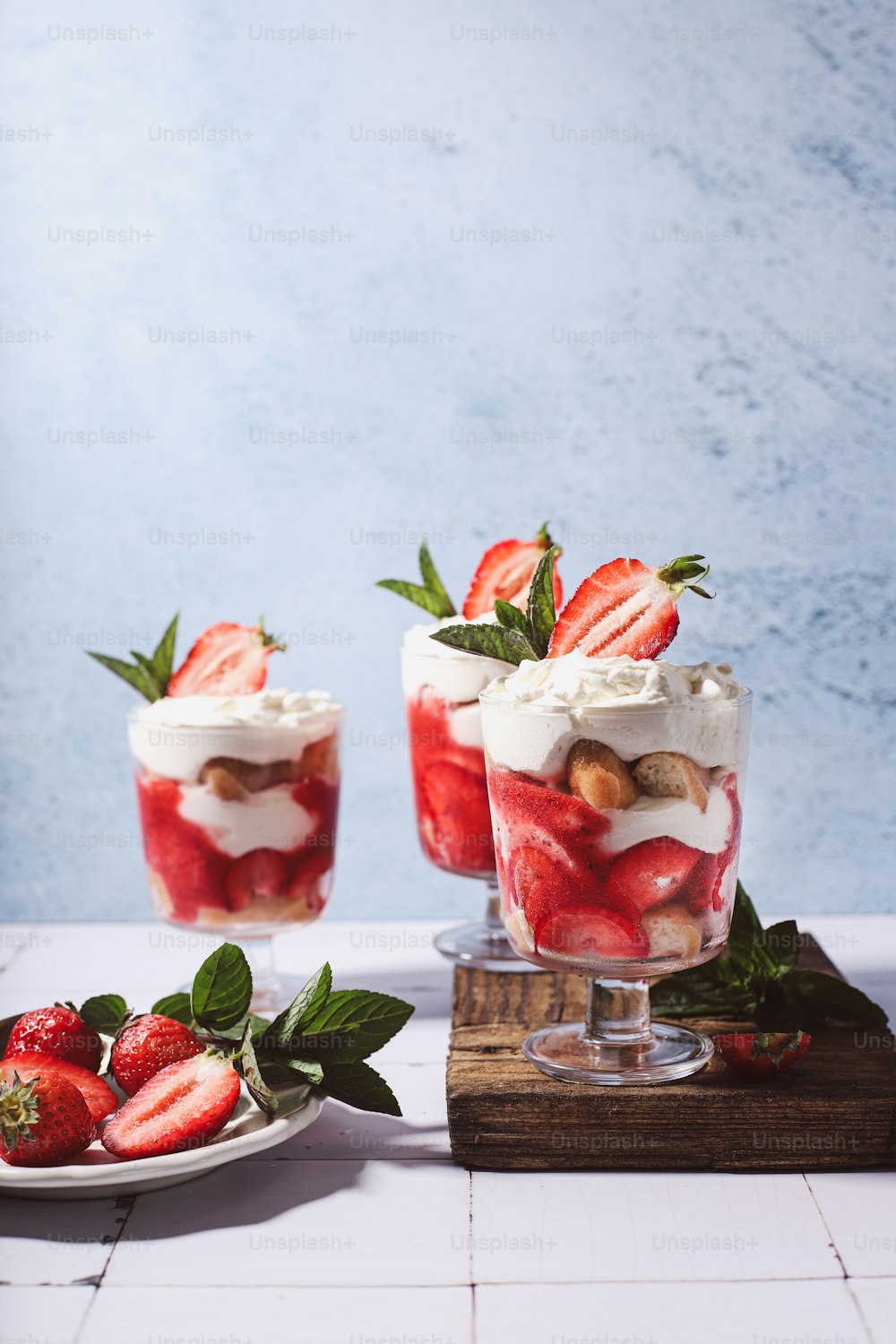three desserts with strawberries and whipped cream on a table