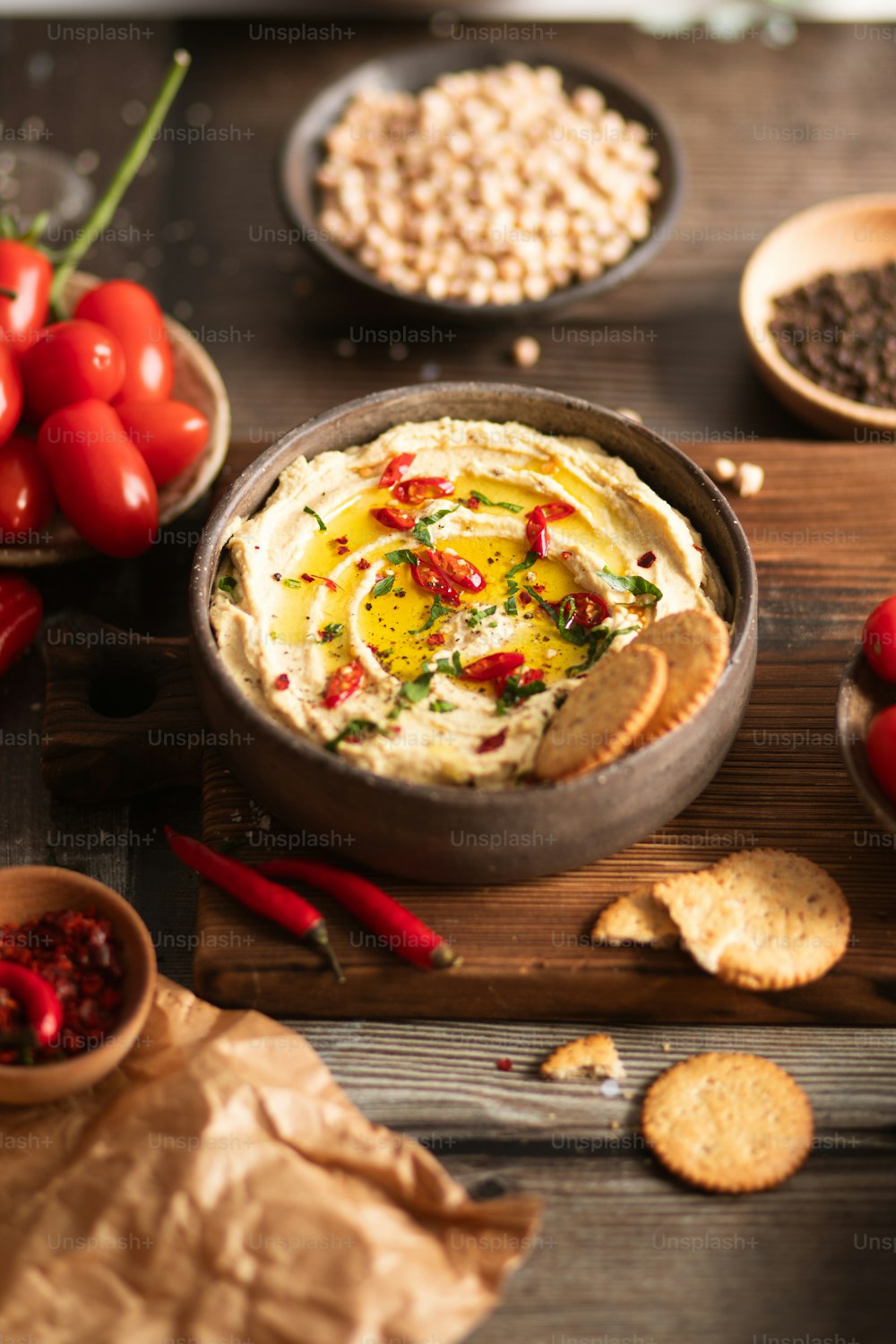 a bowl of hummus surrounded by crackers and tomatoes