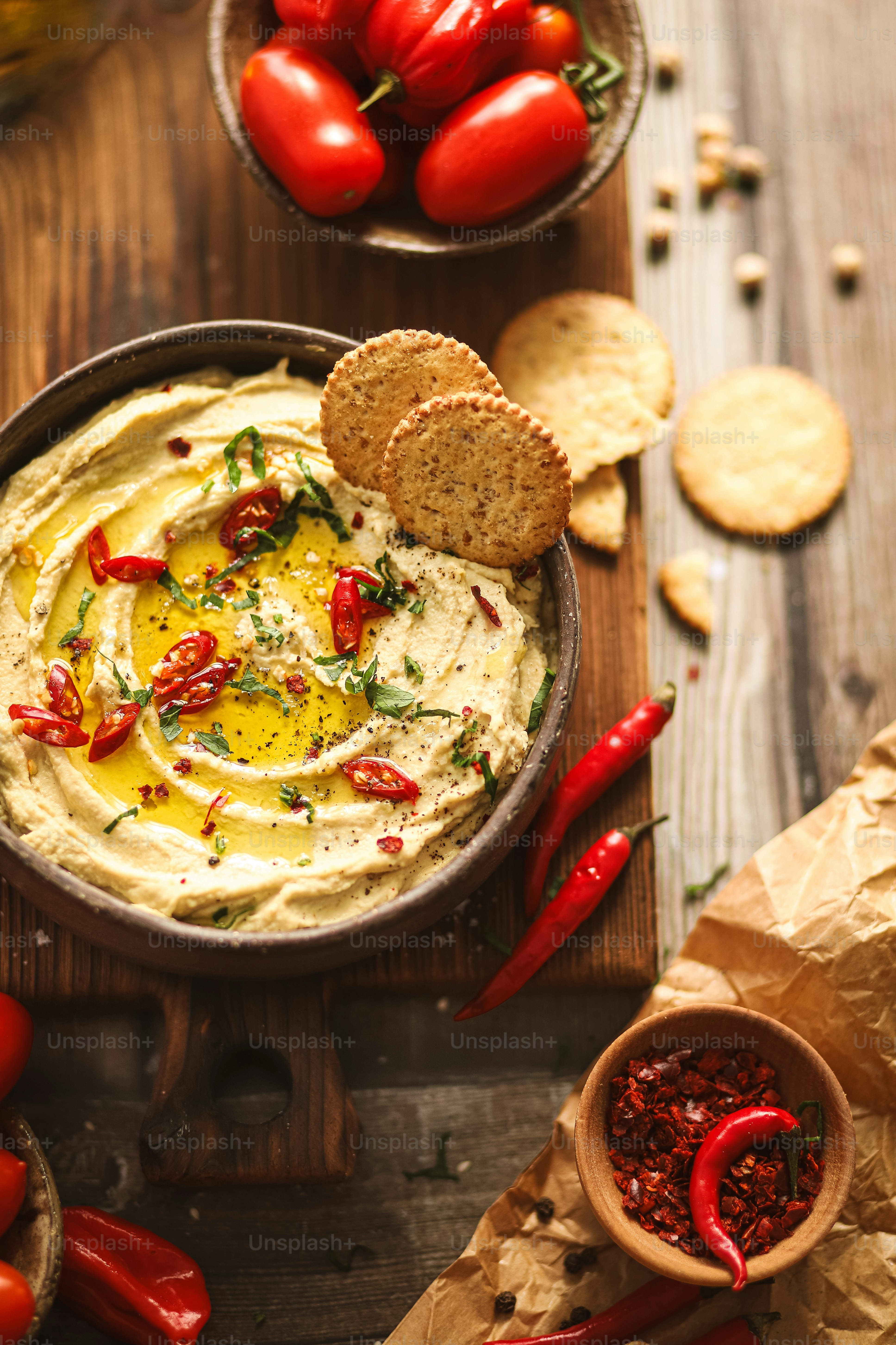 a bowl of hummus with red peppers and crackers