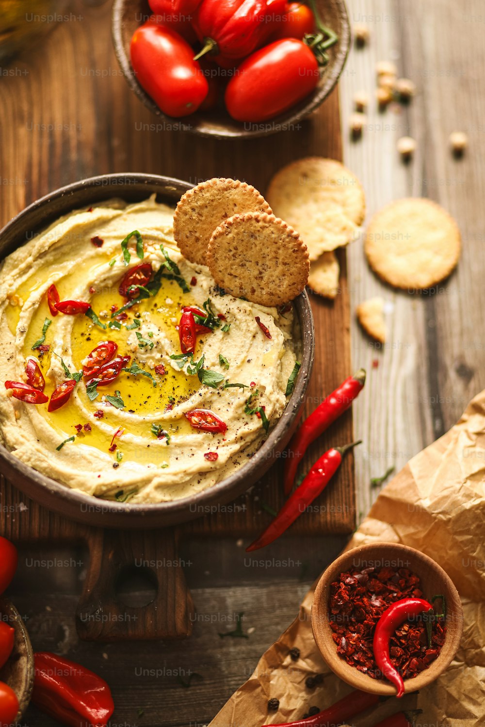 a bowl of hummus with red peppers and crackers