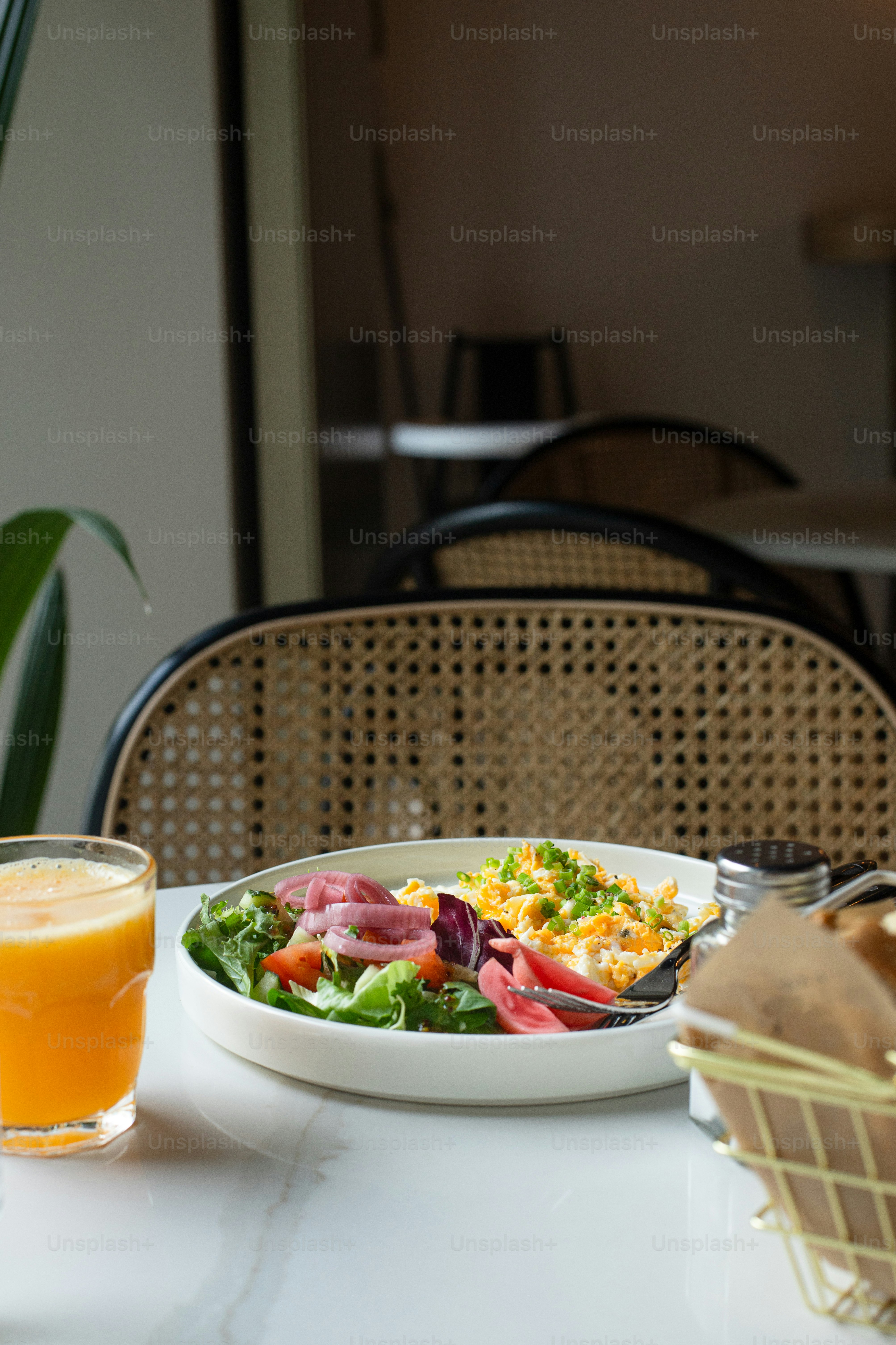a bowl of salad and a glass of orange juice on a table