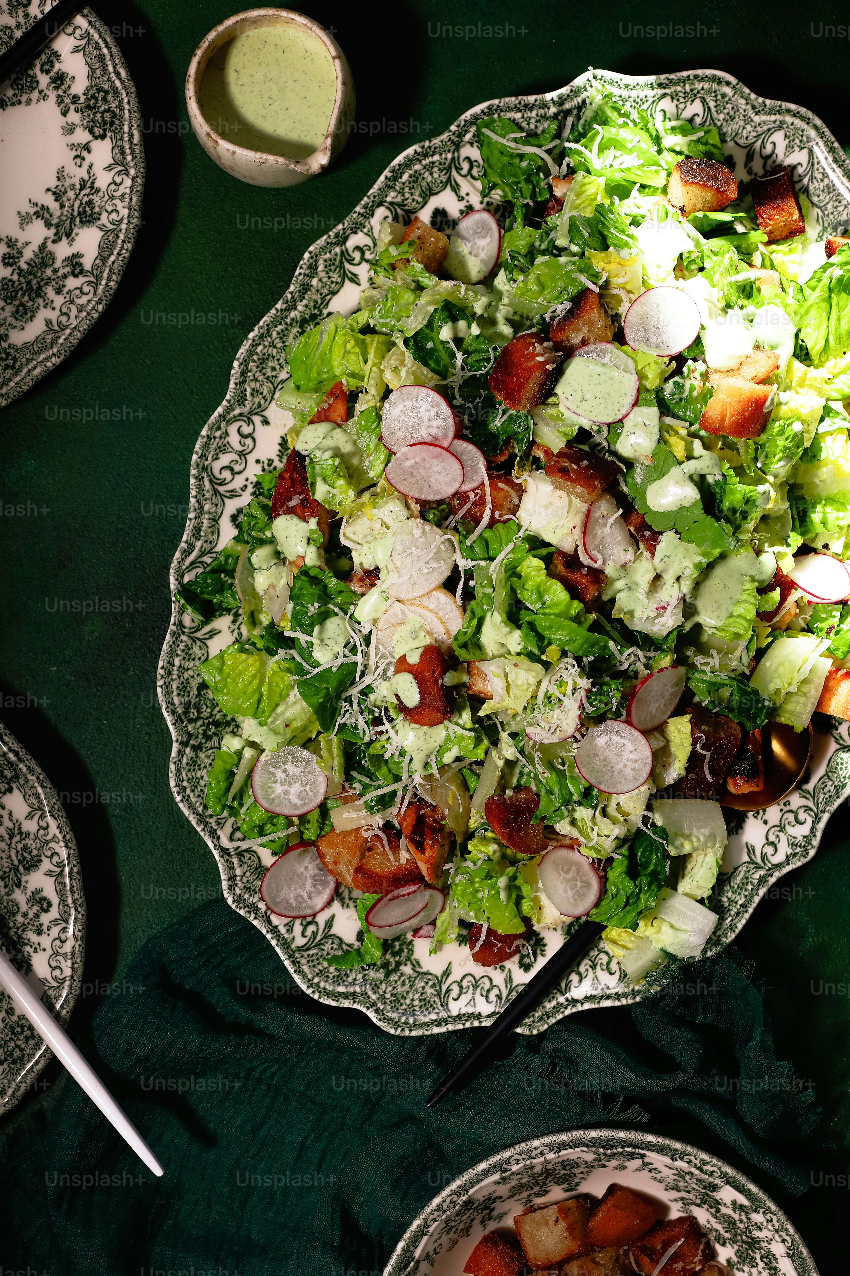 a plate of salad and a bowl of dressing on a table