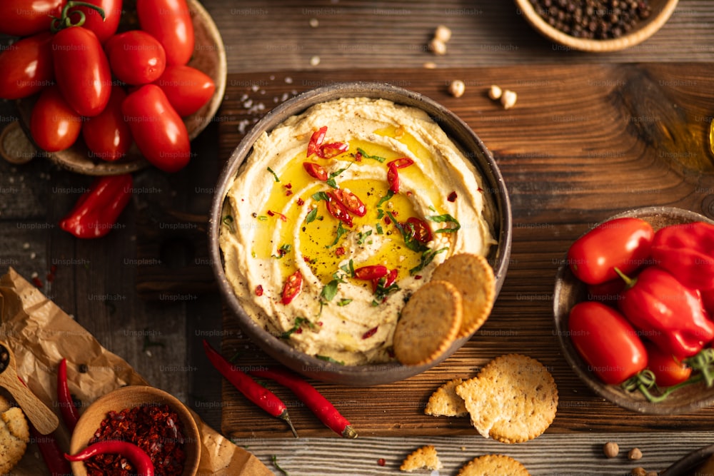a bowl of dip surrounded by crackers and tomatoes