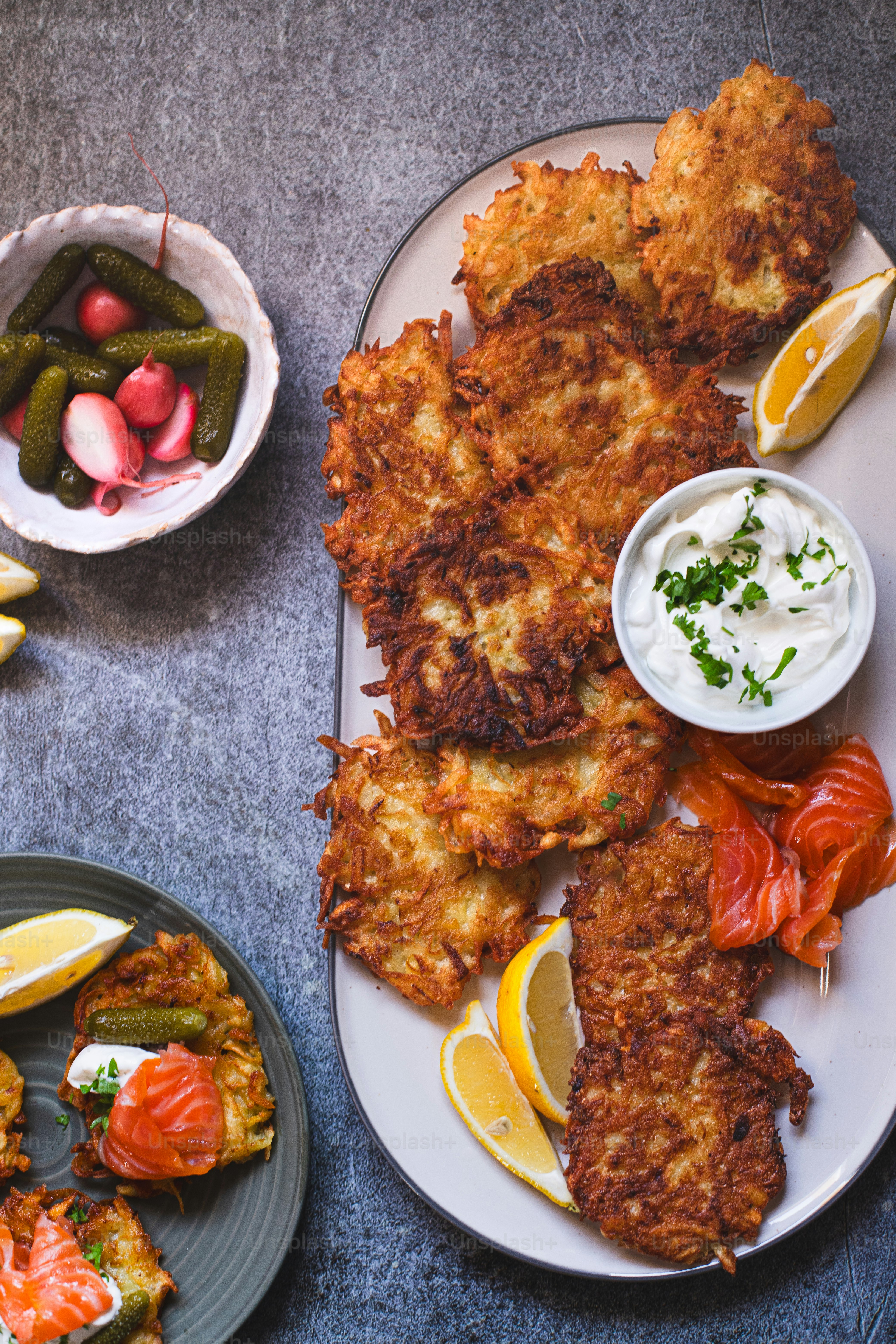 a plate of crab cakes with lemon wedges, pickles, and pickles