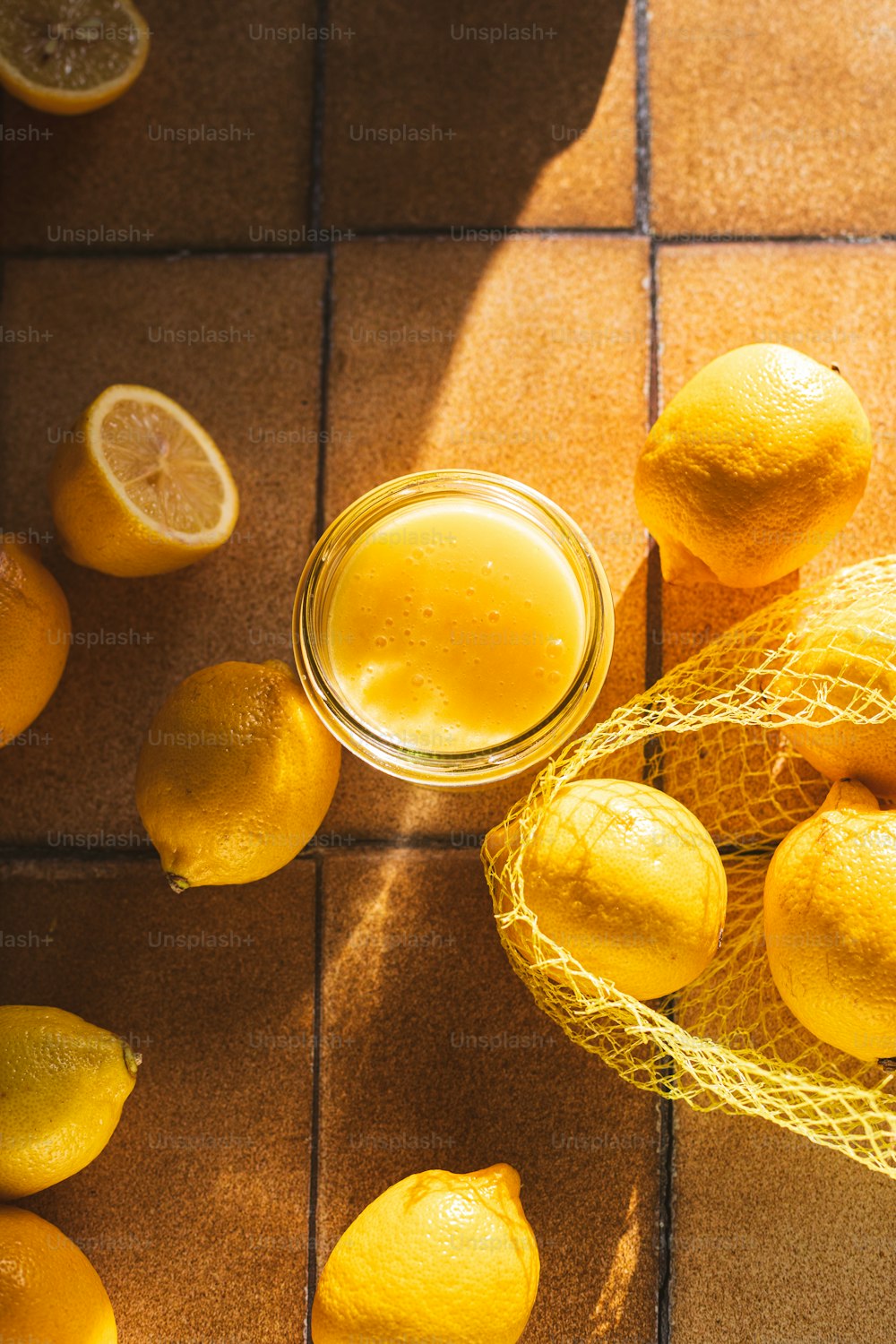 un frasco de limones y algunos limones en un piso de baldosas