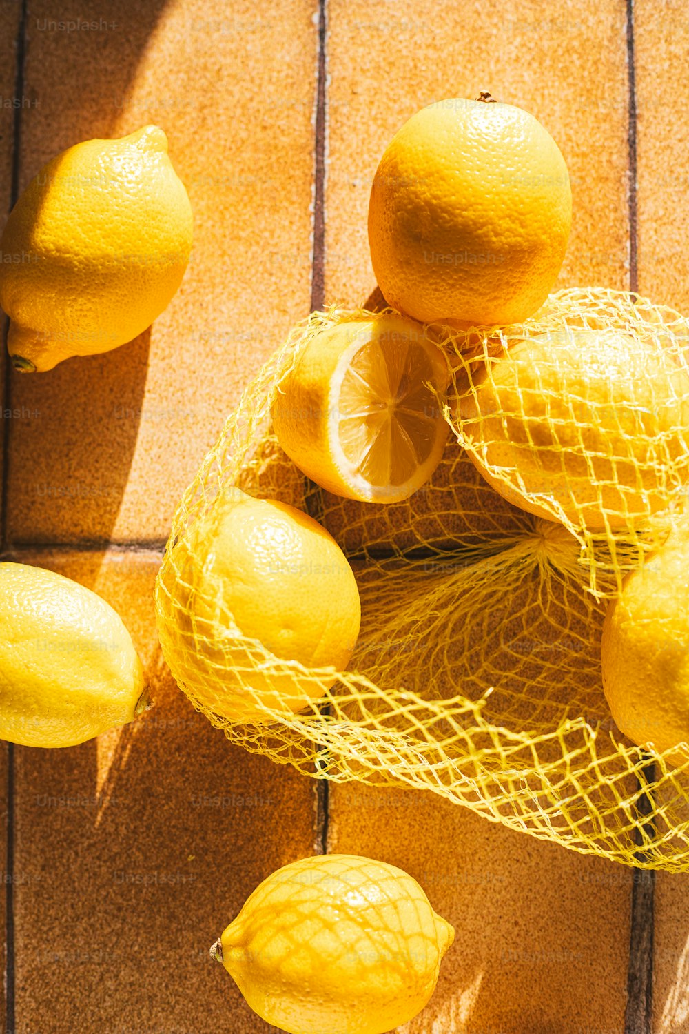 una bolsa de malla llena de limones encima de un piso de madera