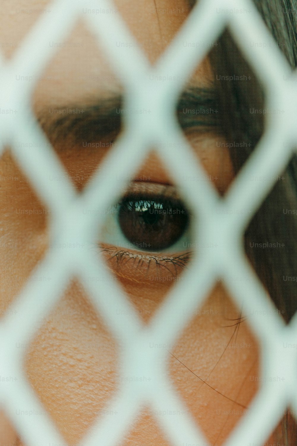 a close up of a person's eye through a chain link fence