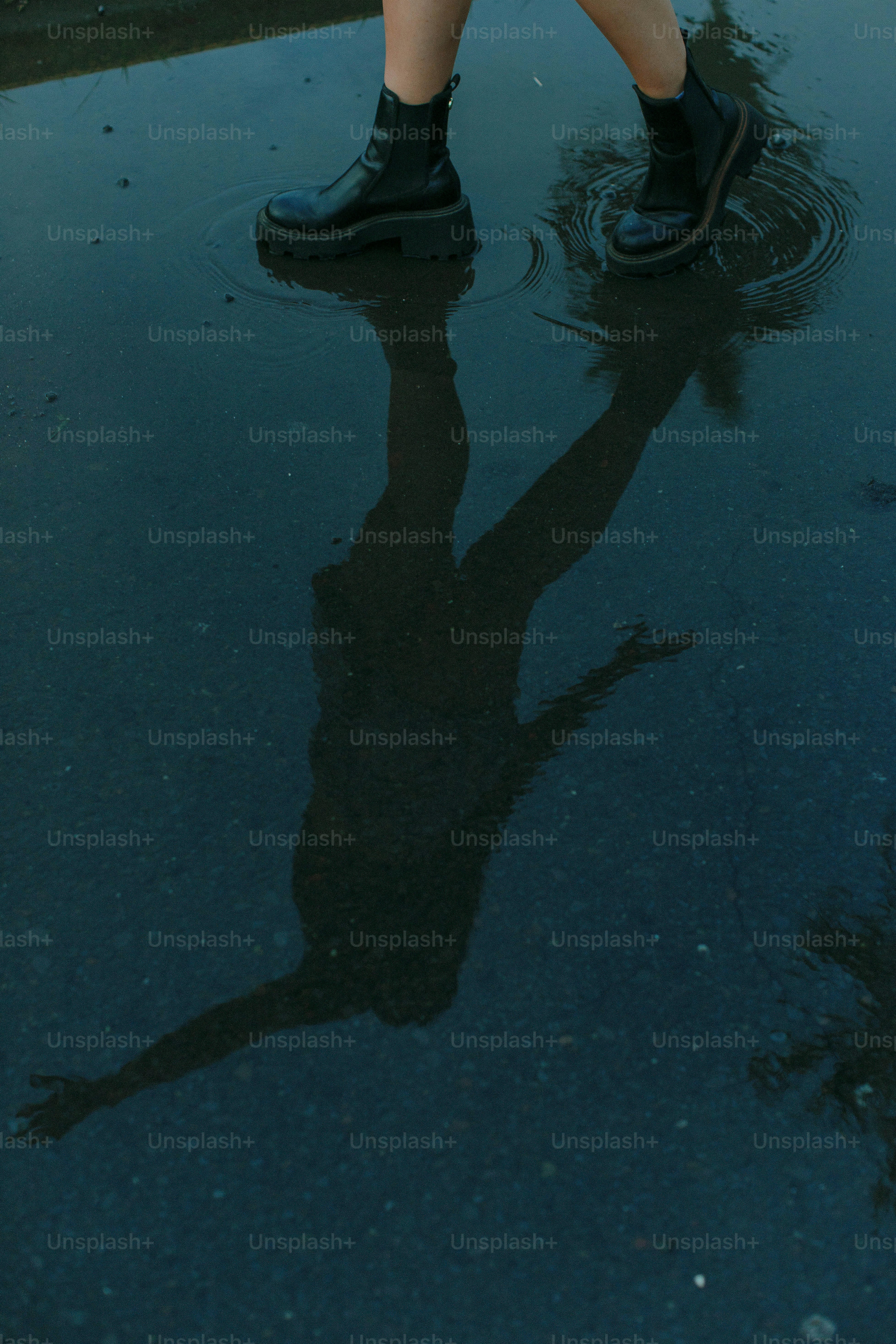a person standing in a puddle holding an umbrella