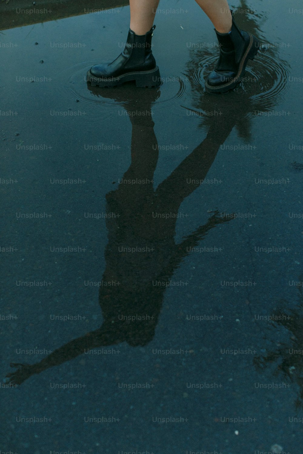 une personne debout dans une flaque d’eau tenant un parapluie