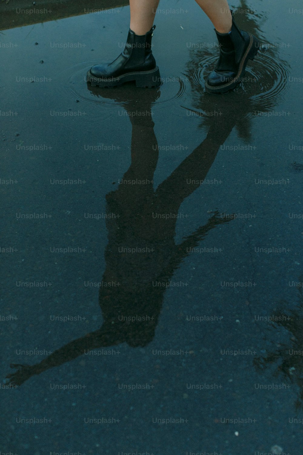 a person standing in a puddle holding an umbrella