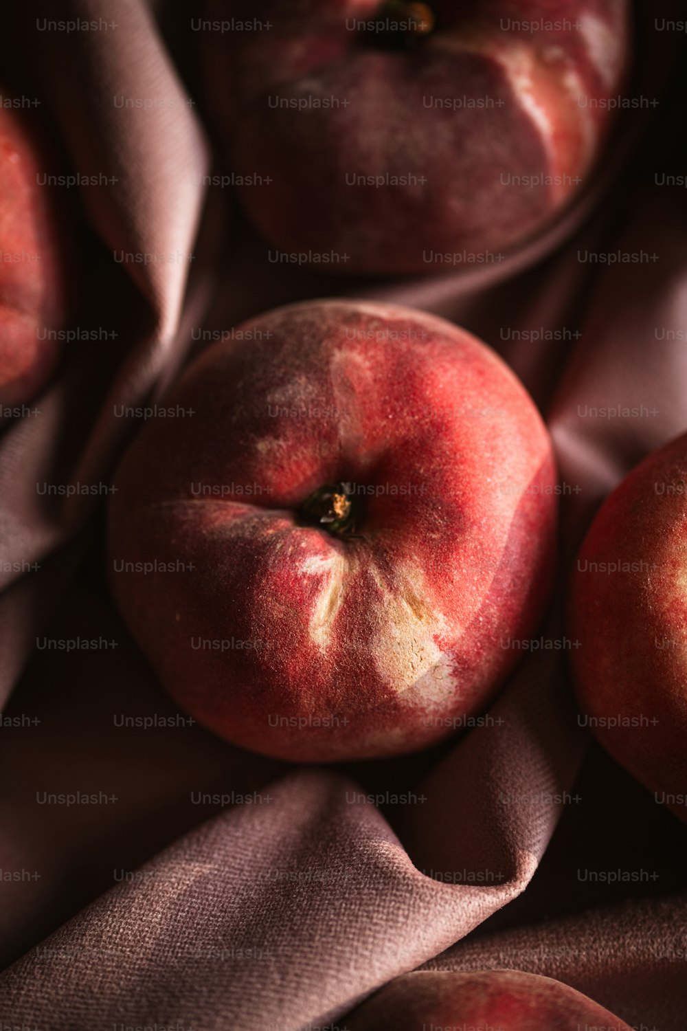 a close up of three peaches on a cloth
