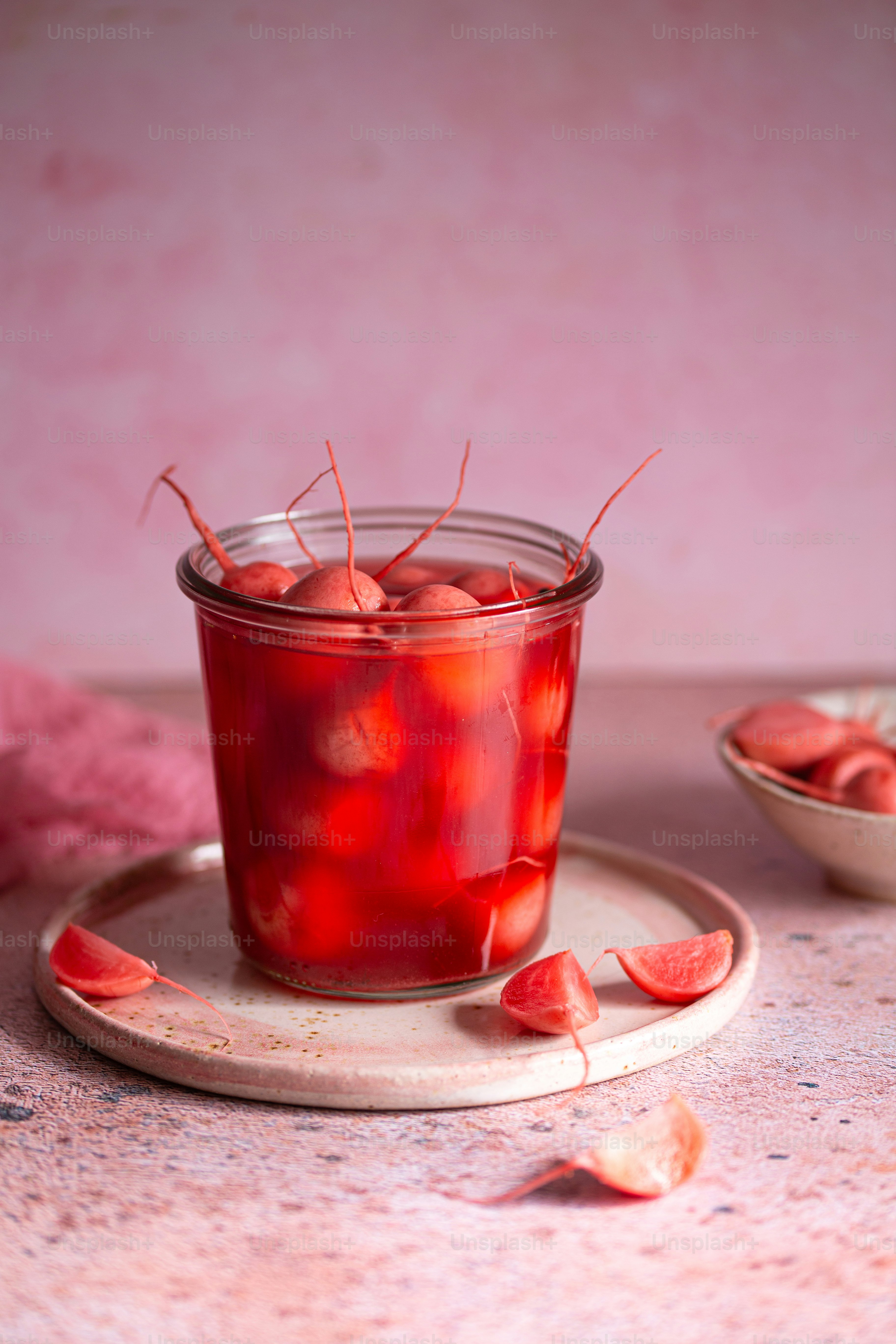a glass of red liquid sitting on top of a plate