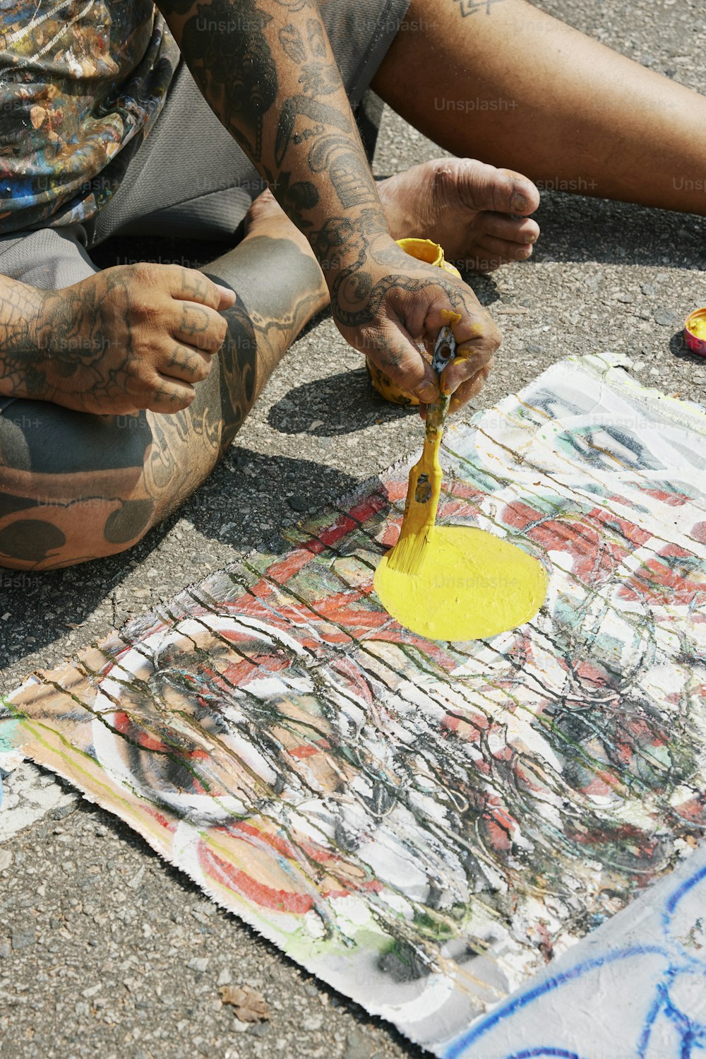 Un uomo seduto a terra con tatuaggi sulle braccia