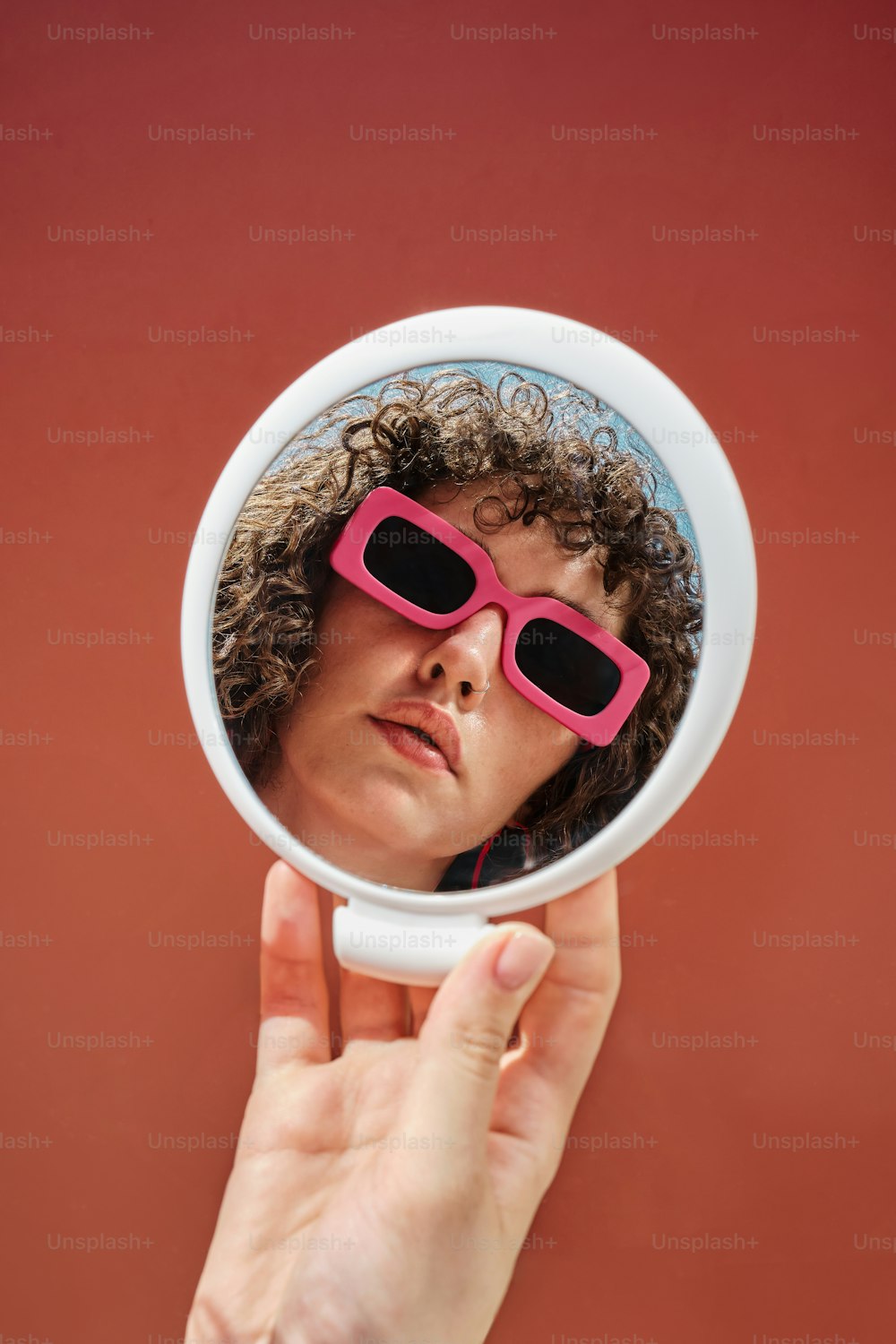 uma mulher usando óculos de sol rosa olhando através de uma lupa