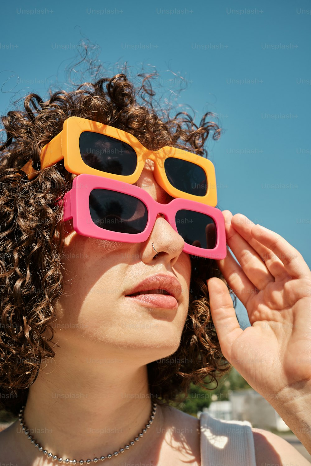 a woman wearing pink and yellow sunglasses with curly hair