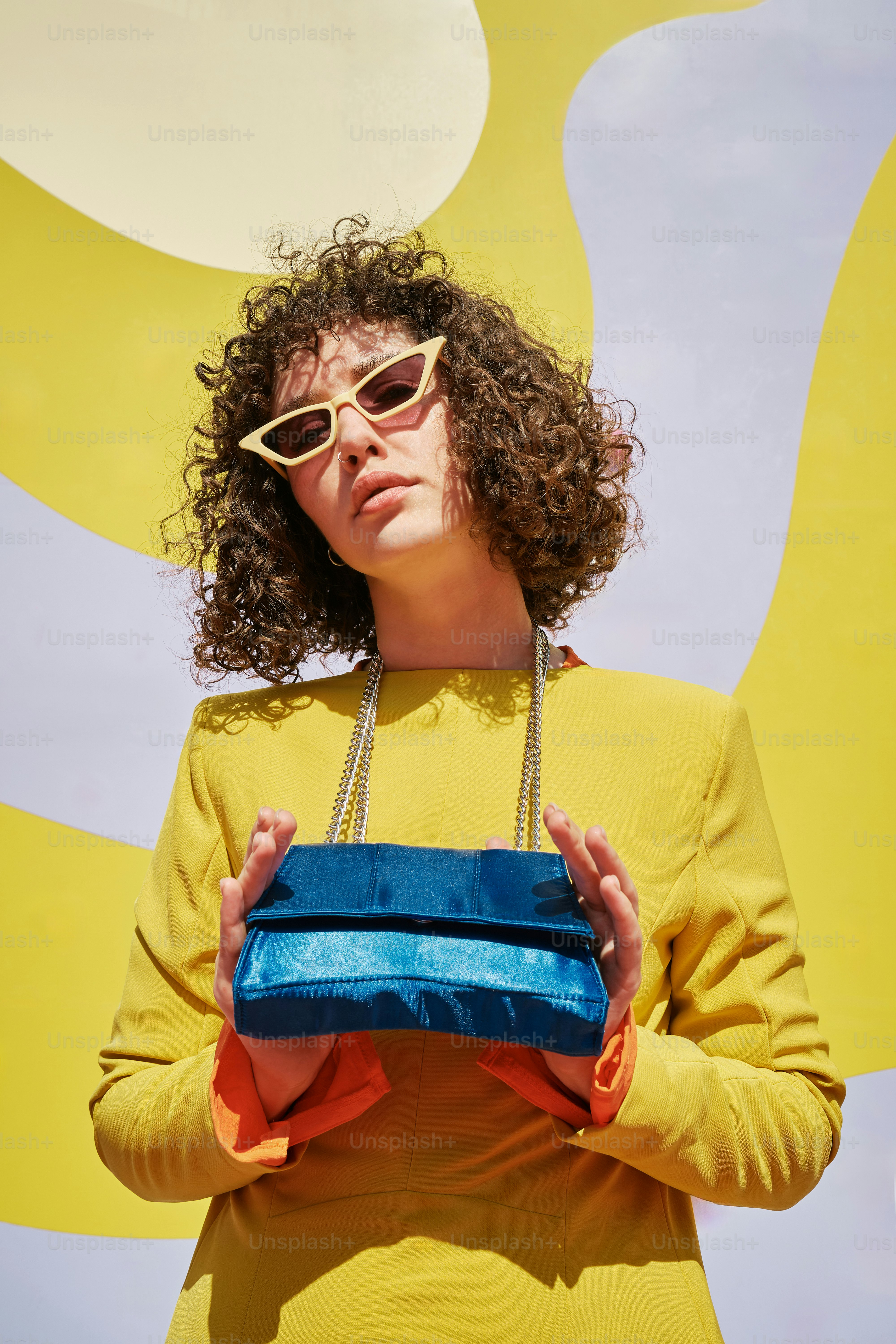 uma mulher em um vestido amarelo segurando uma bolsa azul