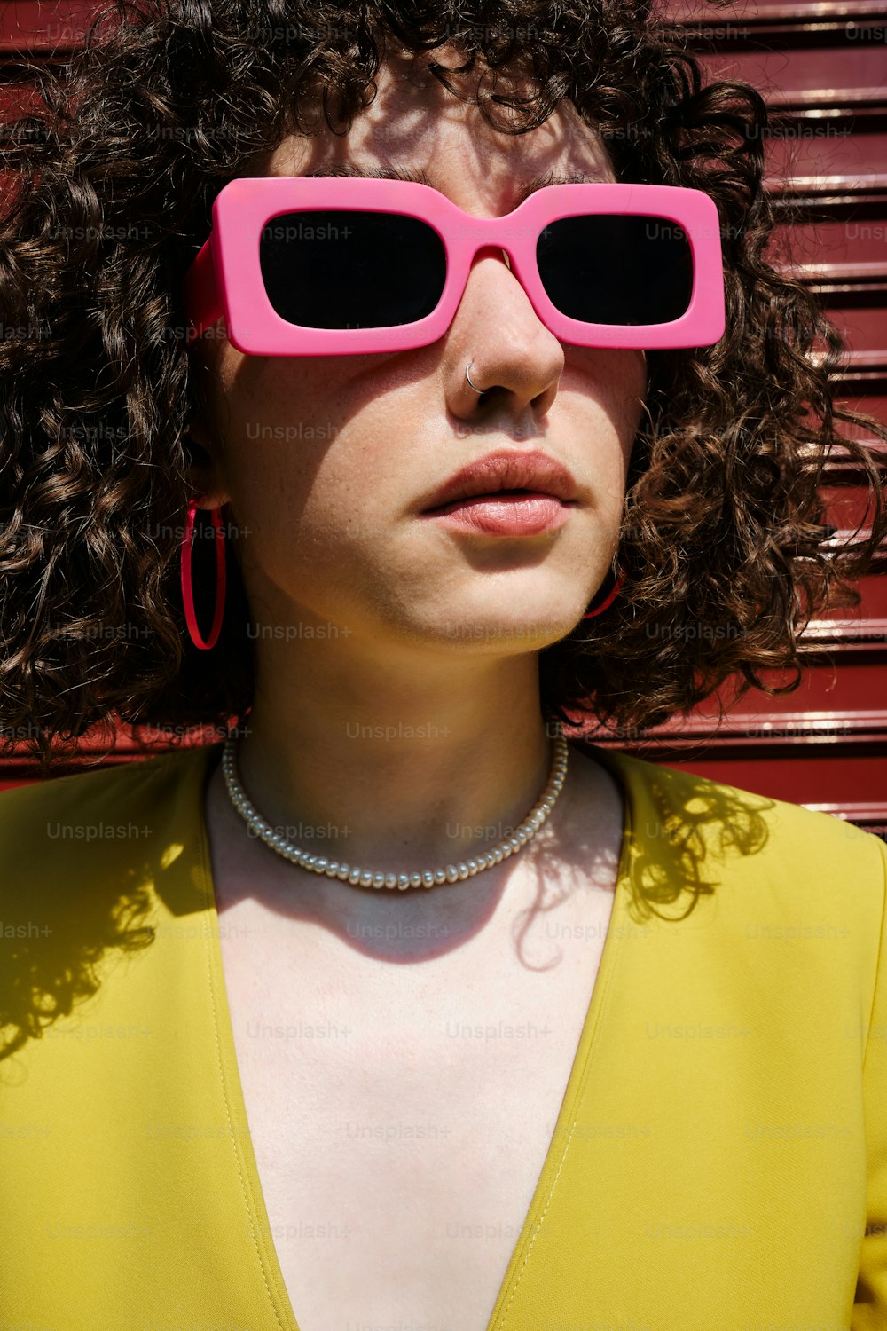 a woman with curly hair wearing pink sunglasses