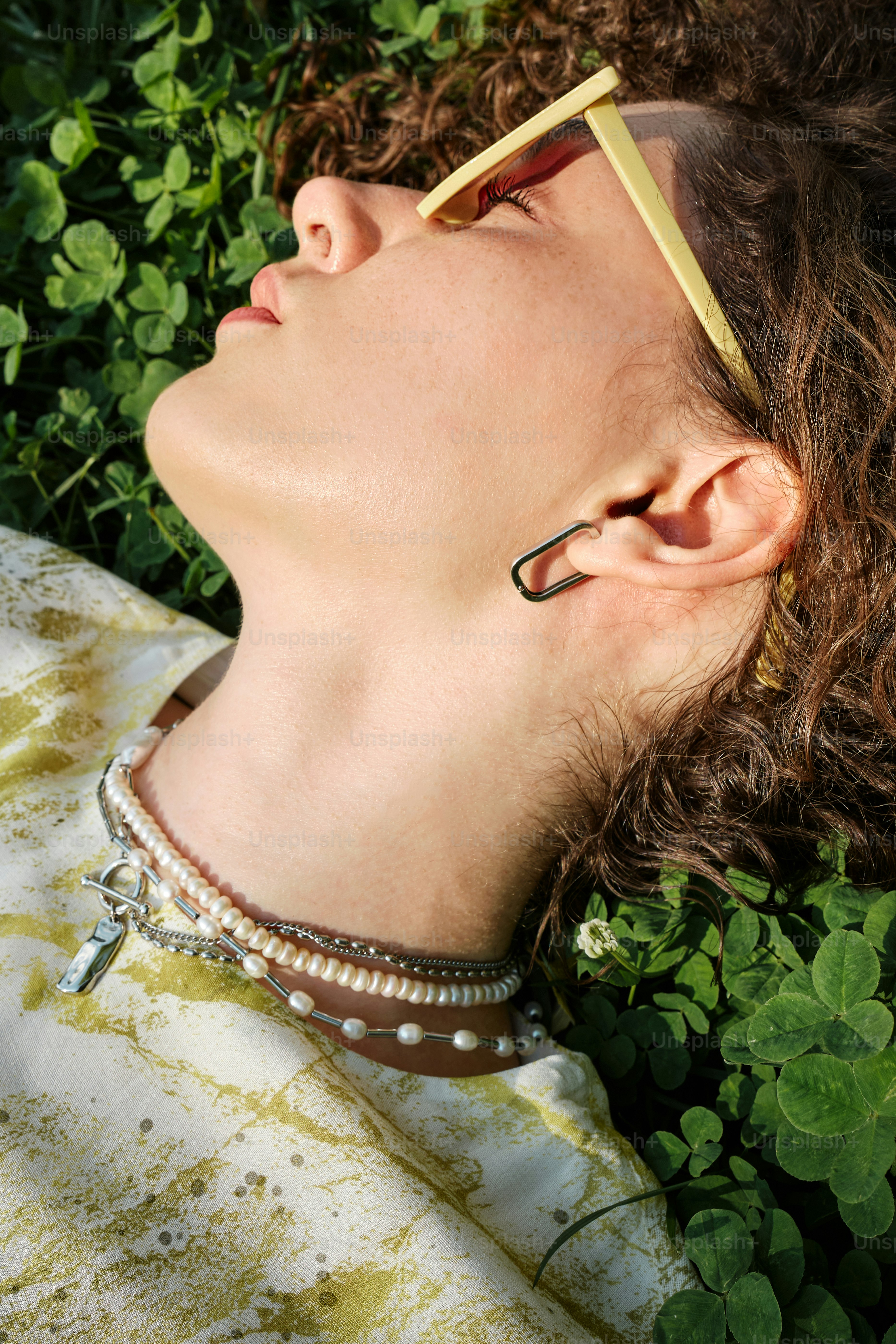 uma mulher deitada na grama de olhos fechados