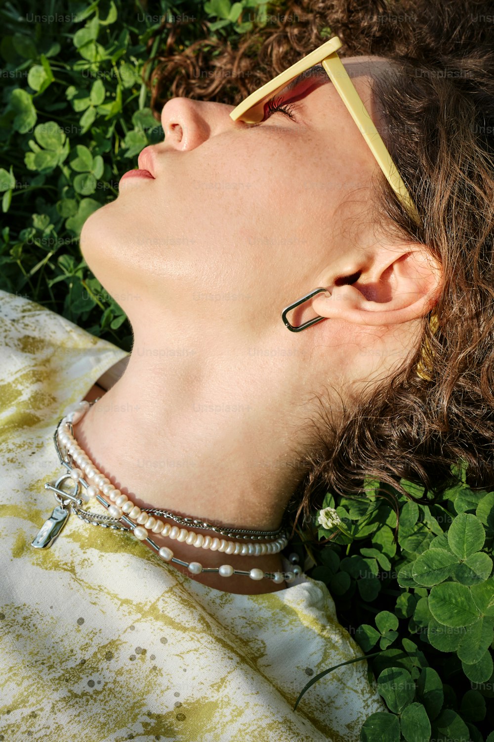 uma mulher deitada na grama de olhos fechados