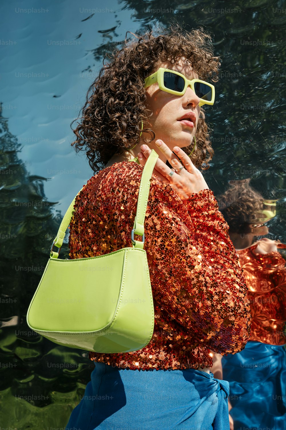 a woman wearing sunglasses and carrying a green purse