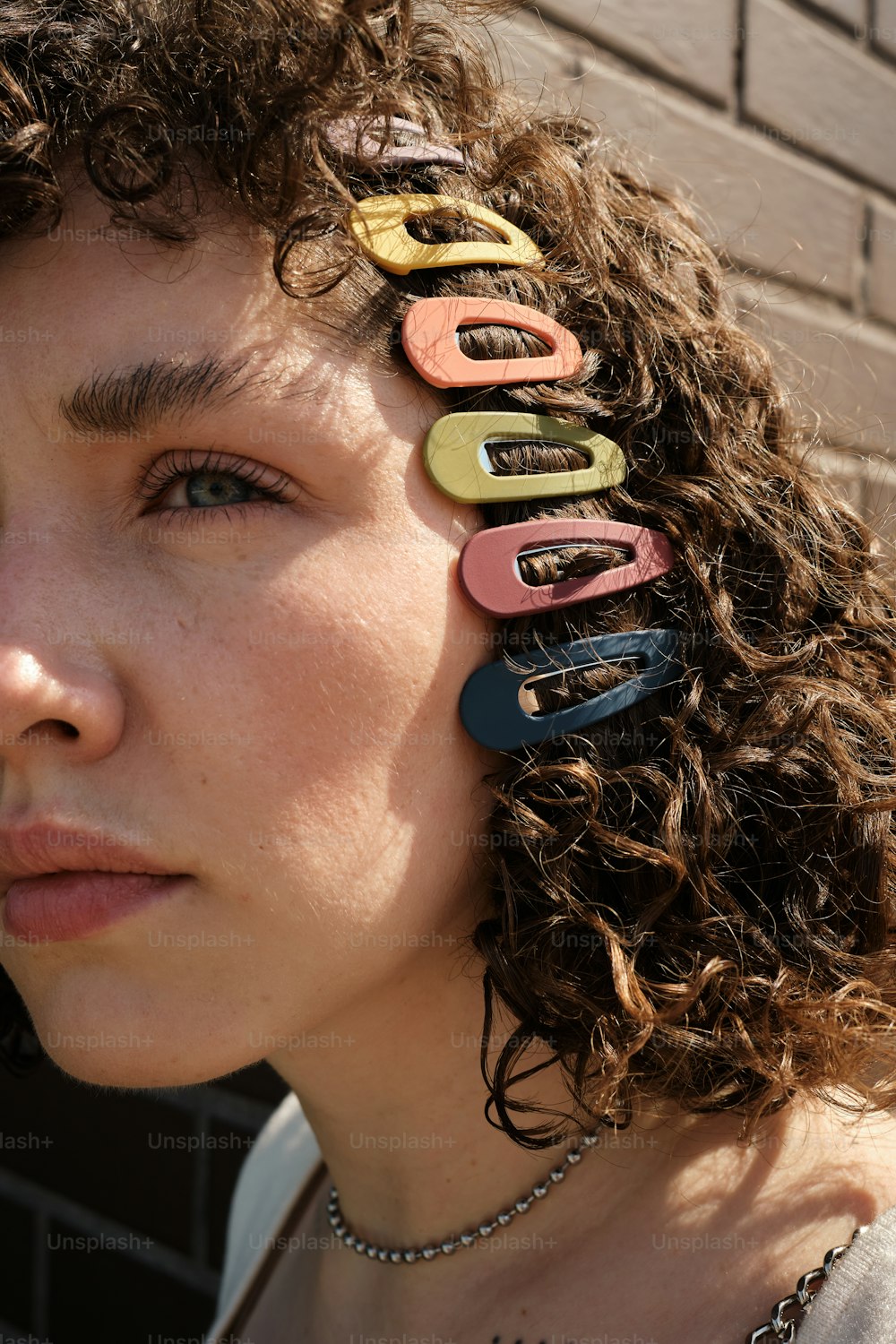 a woman with curly hair has a bunch of hair clips in her hair