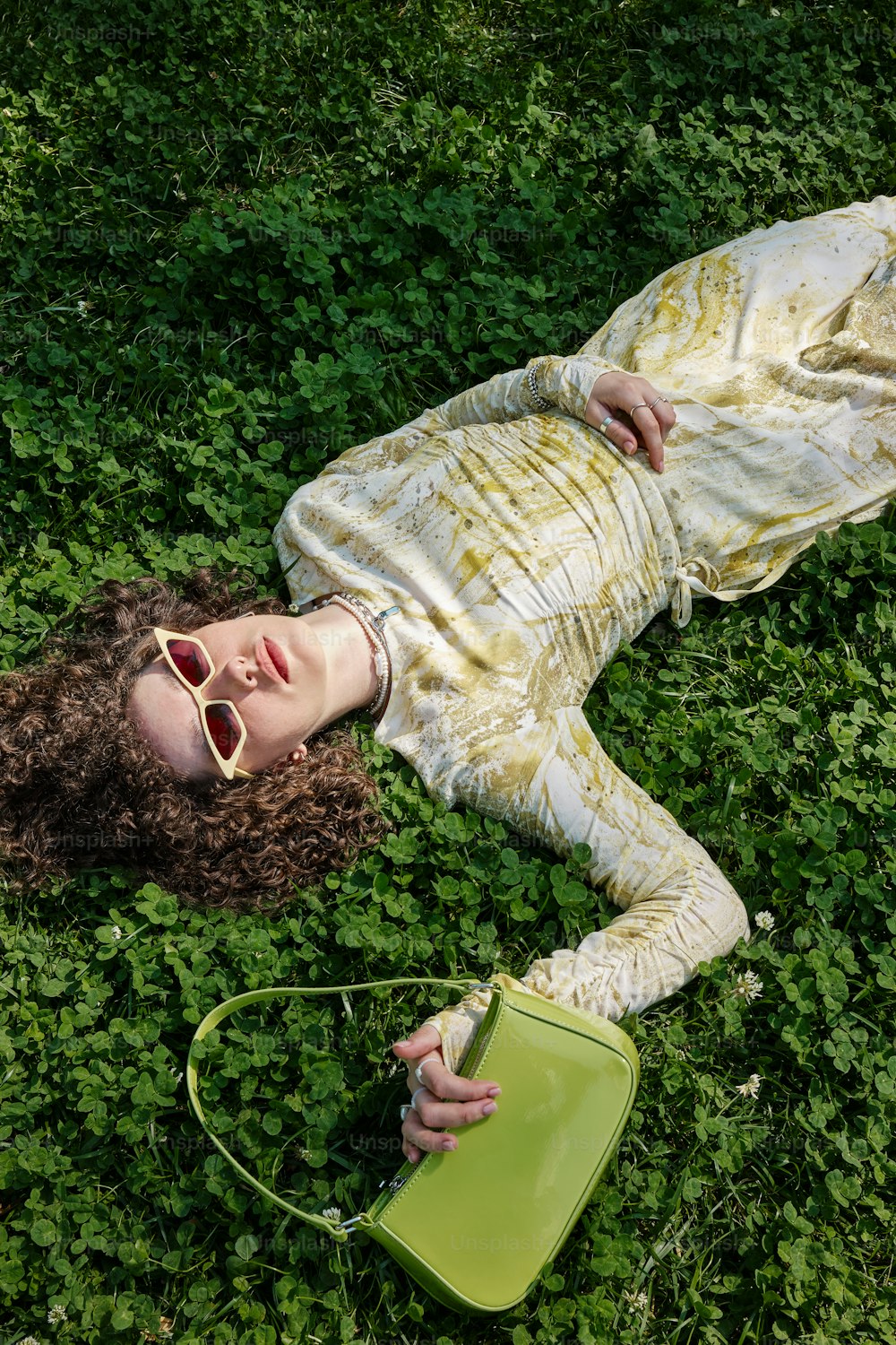 a woman laying on the ground with a green purse