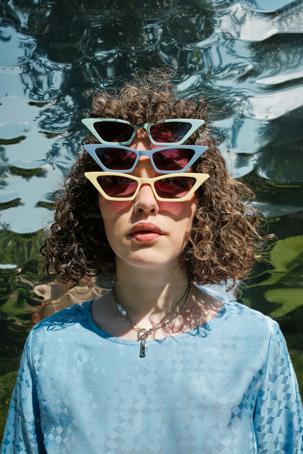 une femme portant des lunettes de soleil debout devant un plan d’eau