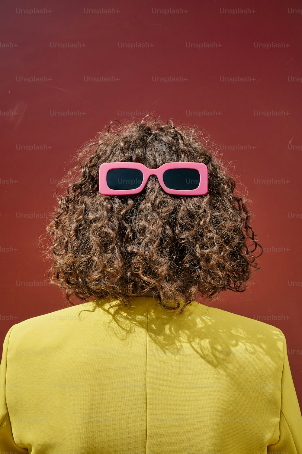 a woman with curly hair wearing pink sunglasses