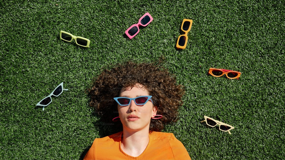 uma mulher deitada na grama usando óculos escuros