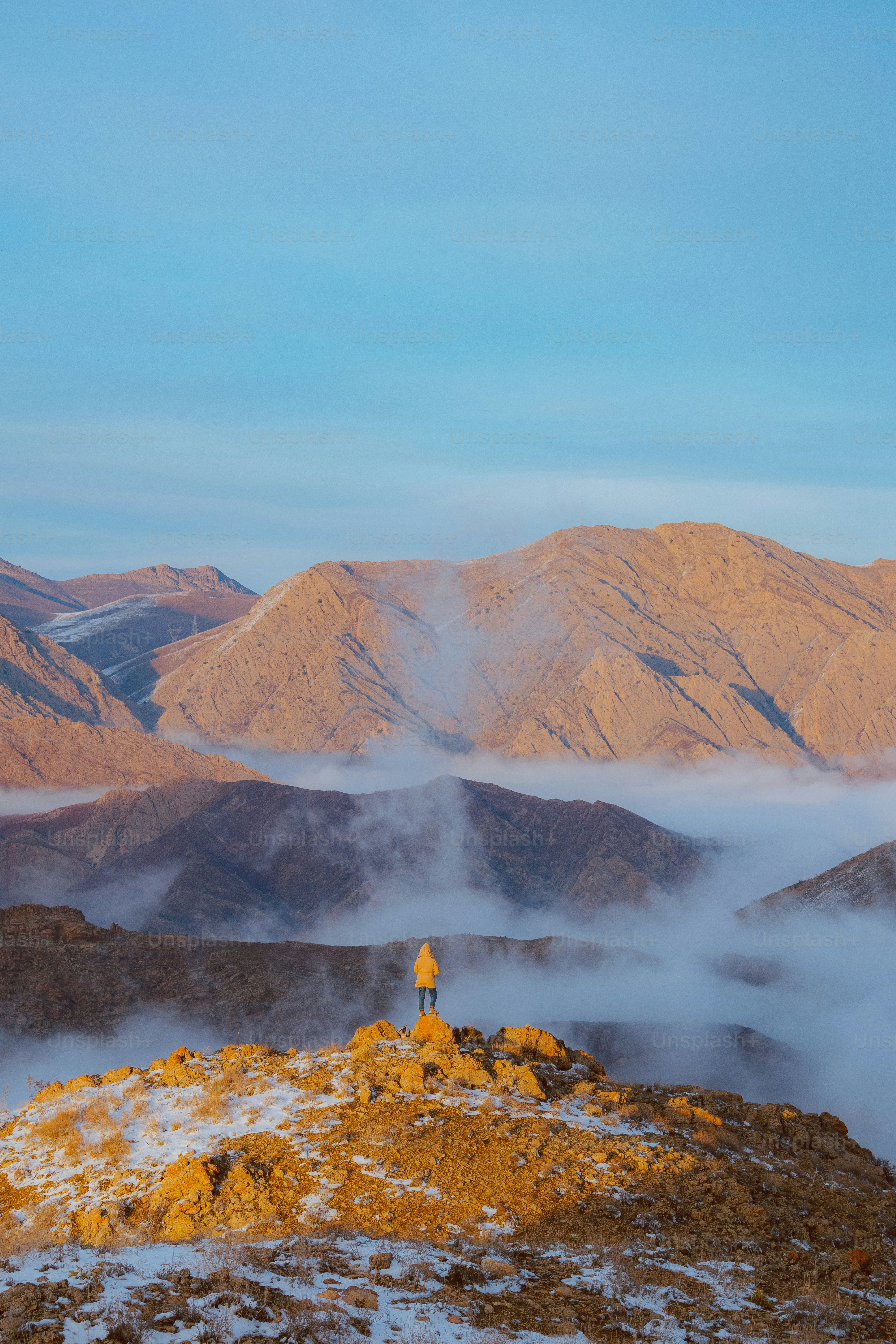 une personne debout au sommet d’une montagne enneigée