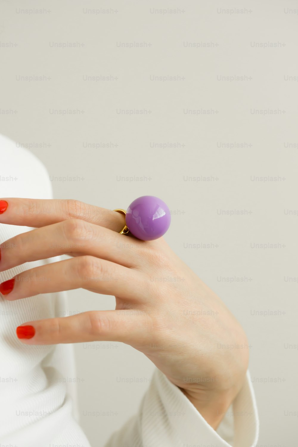 a woman wearing a ring with a purple ball on it